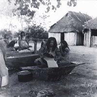 Женщина разбавляет пережёванное тесто из маниока водой